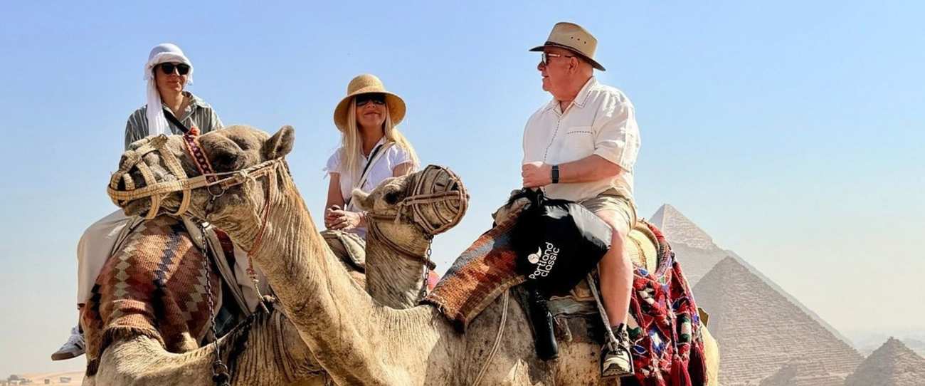 Tres viajeros a camello frente a las Pirámides de Giza