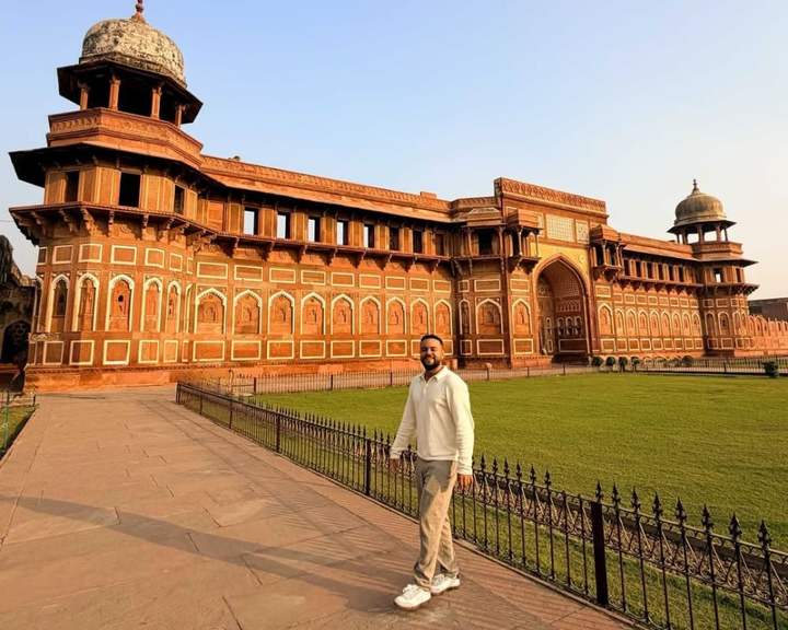 Viajero en el pasto frente al palacio de arenisca roja Jahangiri Mahal, en el Fuerte de Agra, India